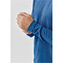 A close-up of a man's hand adjusting the sleeve of a blue long-sleeve crew neck shirt, featuring a logo.