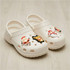 A pair of white clogs featuring festive shoe charms, including Santa and a snowman.