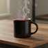A black coffee mug with a pink interior, emitting steam, placed on a wooden surface.