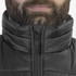 A black puffer vest with a high collar and zip front, worn by a person with a beard. The vest has a branded logo.