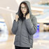 A woman wearing a grey puffer jacket with a hood, featuring a zipper and pockets, in a shopping mall setting.