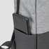 A grey backpack with a black section and a phone stored in a side pocket. It features a logo.