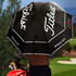 A black double canopy umbrella with a logo, held by a person near a golf course.