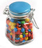A glass clip lock jar filled with colourful M&Ms, featuring a blue lid and a clear container.