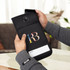 A black lockable phone pouch with a colourful logo, held in hands, designed for secure phone storage.