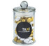 A clear glass apothecary jar filled with yellow and white chocolate beans, featuring a round black logo.