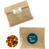 A kraft paper bag filled with colourful Skittles, featuring a logo on the front.