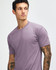 A purple American Apparel tri-blend t-shirt, featuring short sleeves and a round neck. The model has tattoos.