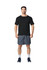 A man stands wearing a black Gildan Performance adult T-shirt and grey shorts, with sports shoes and socks.