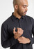 A black long sleeve shirt on a model, featuring a collar and button-up design. The model is adjusting his shirt.