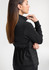 A women's black tailor jacket with a cinched waist, featuring a sleek design and a logo on the back.