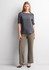 A woman stands wearing grey soft stretch pants and a grey top, complemented by black high heels against a neutral background.