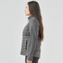 A woman stands sideways wearing a grey Women's Appalachian Thermal Softshell Jacket. The jacket features a quilted design and a logo.