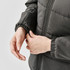 A close-up of a woman's hands adjusting the cuff of a women's grey puffer jacket. The jacket has a logo.
