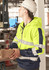 A bright yellow and navy unisex hoodie featuring reflective tape and a logo, worn by a person in a construction setting.