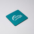A square coaster in teal featuring a logo, with a black edge.