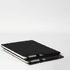 A black A4 notebook stacked with a pen, featuring a simple design and a logo on the cover.