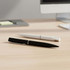 A black pen and a white pen laid on a wooden desk, with a computer in the background. The pens have sleek designs.
