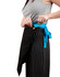 A woman adjusts a black canvas short waist apron with a blue tie, featuring a button and logo.