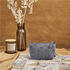 A grey RPET felt mini cosmetic bag is positioned on a textured surface, alongside a candle and a vase with dried foliage.