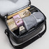 A cooler bag in grey with assorted items, including drinking chocolate, marshmallows, and a wooden stick.