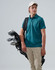 A person wearing a teal polo shirt and beige pants holds a golf bag with clubs, topped with a light-coloured cap.