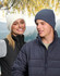 A white and a navy blue cable knit snug beanie displayed on models in outdoor attire, set against a nature backdrop.