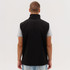 A black softshell vest is displayed, featuring a high collar and a sleek design, with a person wearing it from the back.