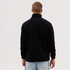 A black polar fleece 1/4 zip garment viewed from the back, worn by a person with short hair and a casual outfit.