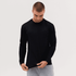 A long sleeve tee in black, worn by a model inspecting the hem, with a casual fit and long sleeves.