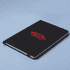A black A5 notebook with a logo on the cover and an elastic closure, set against a light blue background.