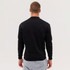 A man is wearing a black sweatshirt, facing away, with light grey trousers. The sweatshirt features a logo.