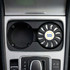 An air freshener in a circular black holder, placed in a car cup holder, featuring a logo.