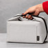 A grey recycled lunch cooler bag with a handle and a branded tag, being held by a hand.
