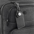 A black luggage tag with an AirTag holder attached to a grey suitcase, featuring a logo on the suitcase.