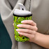 A drink bottle covered with a green neoprene sleeve featuring lime and olive designs, held in a person's hand.