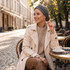 A customised elastic headband in grey is worn by a woman sitting at a café table outdoors, enjoying a coffee.