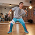 A boy dances in custom youth active pants, featuring a vibrant teal and purple design, with a casual grey t-shirt.
