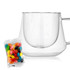A clear coffee cup with a unique diamond shape alongside a packet of colourful jelly beans.