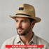 A Panama straw hat in natural tones with a black ribbon band, featuring a logo on the front.