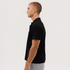 A black polo shirt displayed on a model from the side, featuring a collar and short sleeves.