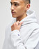 A light grey pullover hooded sweatshirt featuring a logo, worn by a young man with short hair.