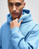 A pullover hooded sweatshirt in light blue, featuring a logo on the sleeve.