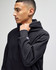 A black pullover hooded sweatshirt with a logo, worn by a model, showing the hood and sleeve.