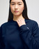 A woman wearing a navy blue crewneck sweatshirt featuring a logo on the sleeve.