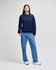 A navy blue crewneck sweatshirt featuring long sleeves and a logo, paired with light blue jeans.
