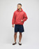 A red pullover hooded sweatshirt with a front pocket, worn by a model with navy shorts. Features a logo.