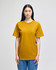 A mustard yellow Champion adult short-sleeve T-shirt displayed on a model. The shirt has a simple logo on it.