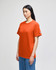 An orange short-sleeve t-shirt displayed on a model, featuring a logo on the sleeve.