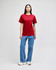 A model wearing a red Champion adult short-sleeve t-shirt paired with blue jeans and white sneakers.